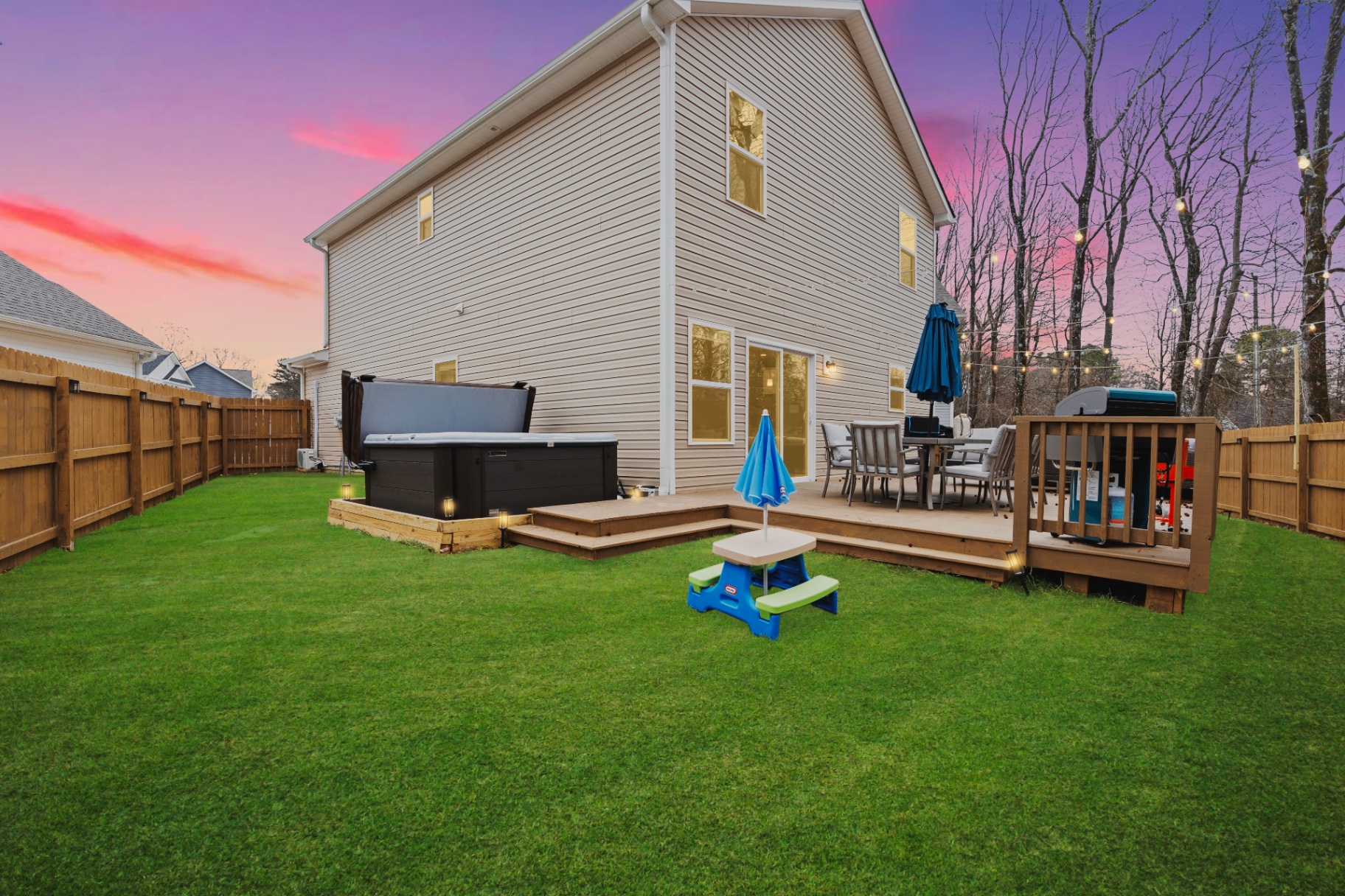 Backyard deck with hot tub and string lights at sunset